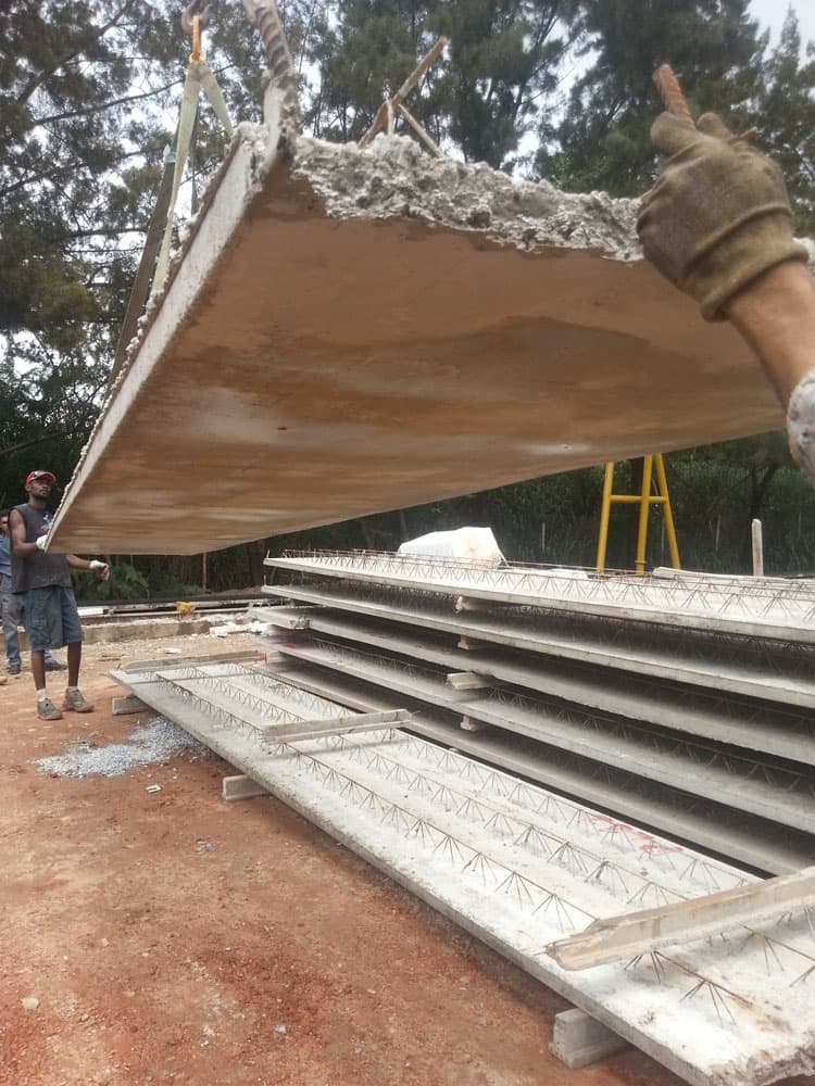 Painel de laje pré-moldada sendo içado em obra